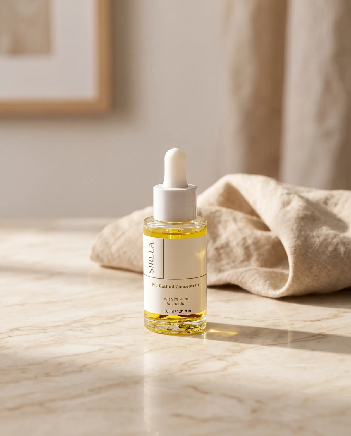 A clear glass dropper bottle of Sirela Bio-Active Concentrate serum oil with pale yellow liquid, standing on a light marble surface next to a beige linen cloth in soft natural light.