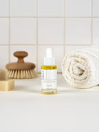 Sirela Bio-Retinol Concentrate serum bottle with dropper on a bathroom counter with a brush and towel in the background.
