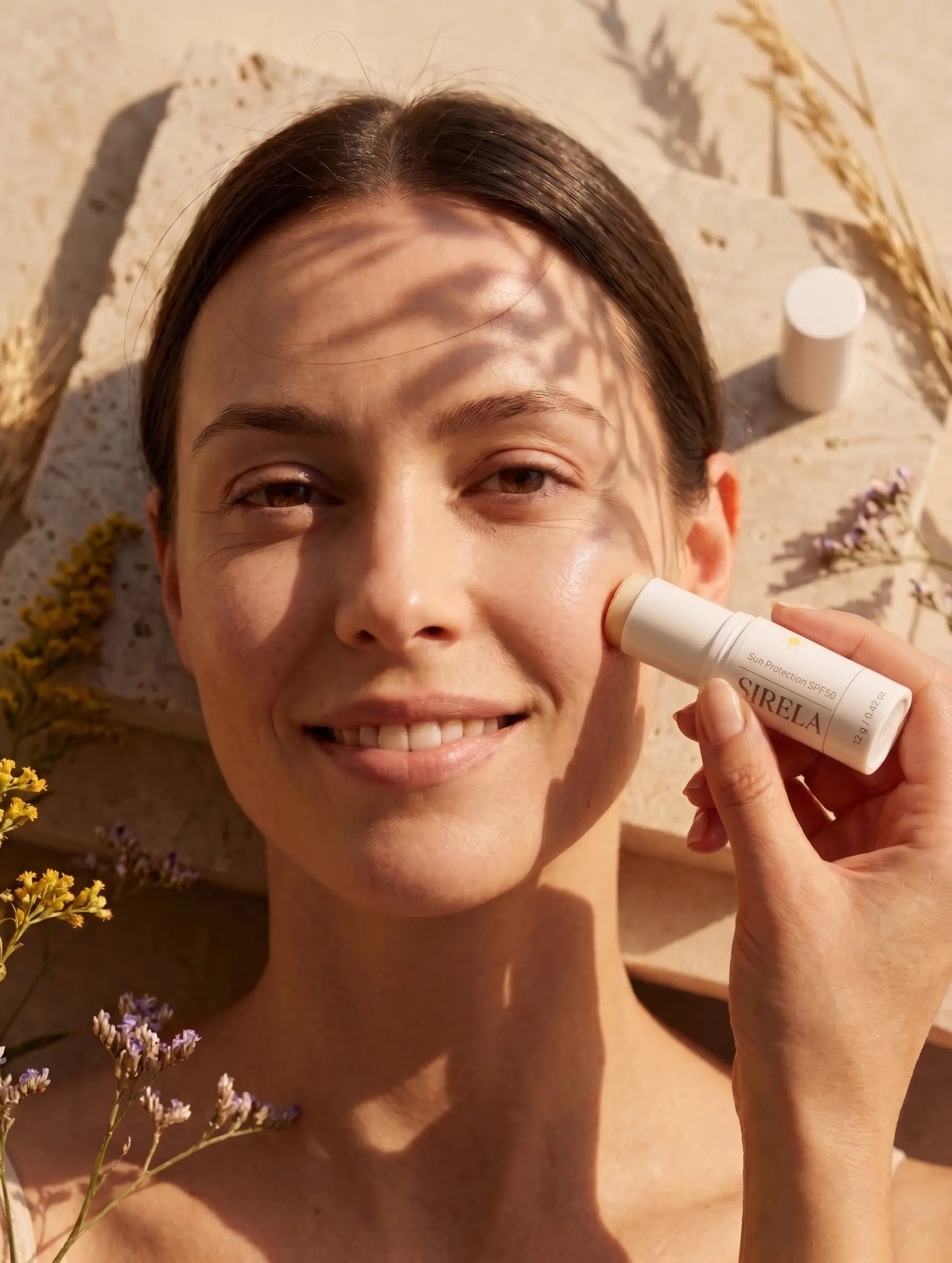 Applying Sirela Mineral SPF 50 Stick — gliding the untinted stick directly onto the cheekbone in natural sunlight