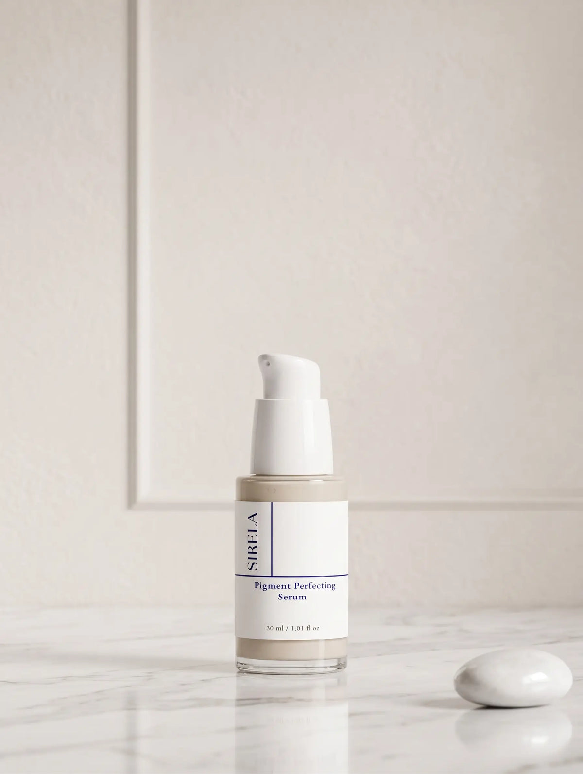 Sirela Pigment Perfecting Serum in a clear bottle with a white pump dispenser, set on a white marble surface against a neutral cream-colored wall.