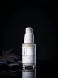 Sirela Pigment Perfecting Serum in a clear glass bottle with a white pump dispenser, set against a dark background with decorative stones and a leaf.