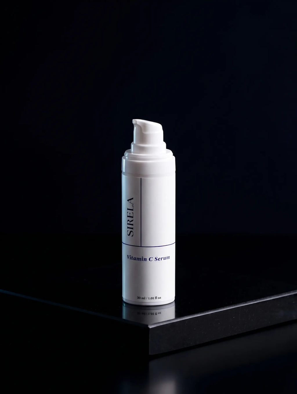 A white cylindrical pump bottle of SIRELA Vitamin C Serum standing upright on a glossy black surface against a very dark black background.