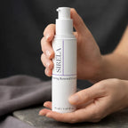 Sirela Firming Renewal Cream bottle held in both hands in a soft spa-like setting, close-up product lifestyle photo with the label clearly visible.